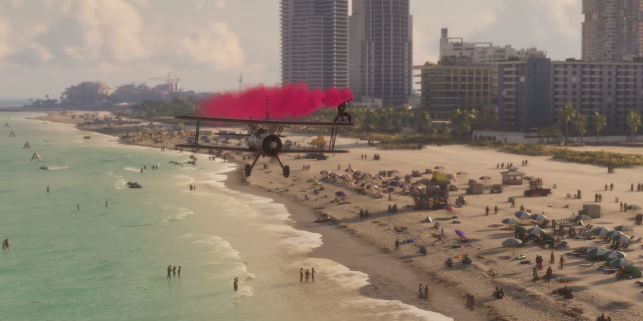 A biplane trailing pink smoke over a crowded beach