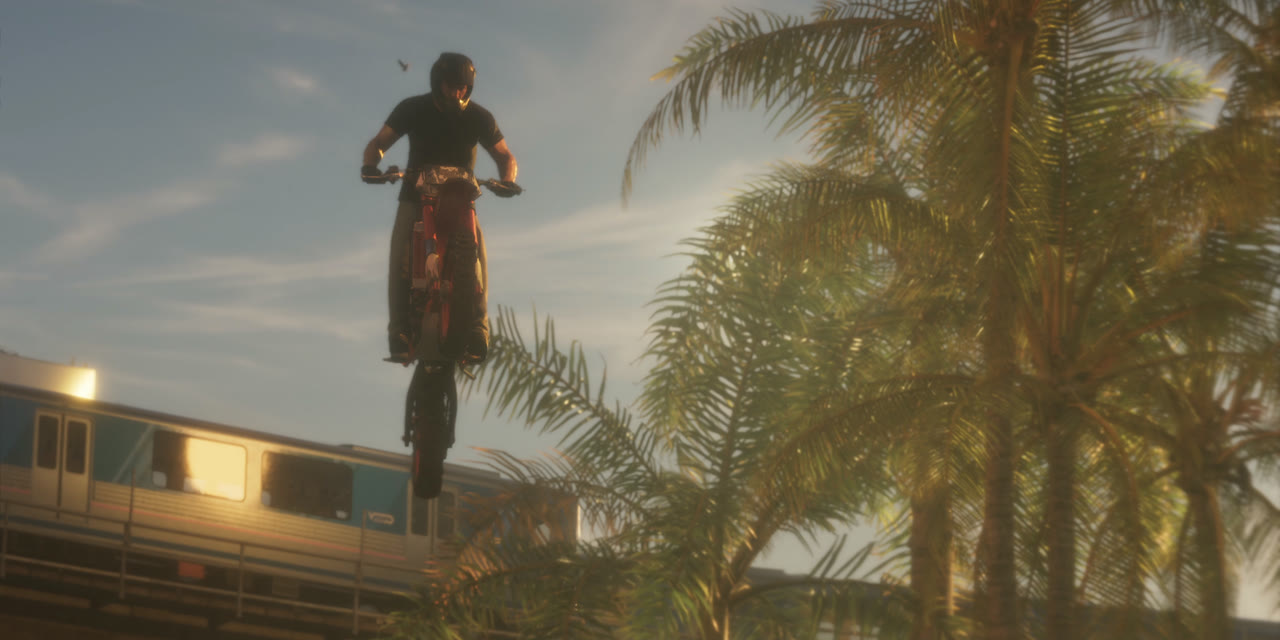 A motorcyclist jumps over an elevated train